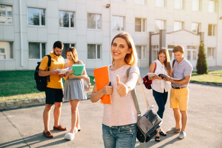 happy-beautiful-girl-standing-with-note-books-backpack-showing-thumb-up-smiling